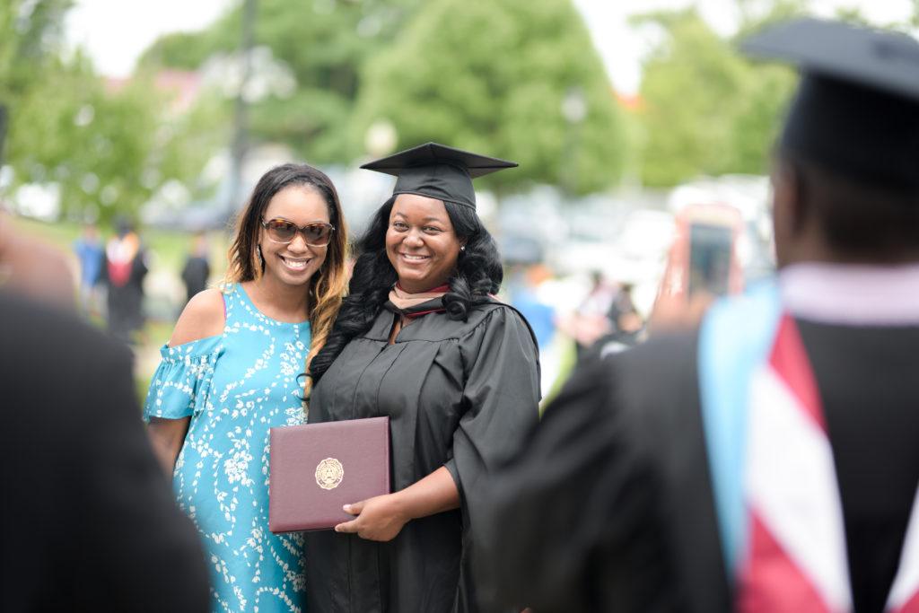 From left, LaKeia Smith of Nicholasville, Ky., takes photos with Sharea Coleman, her cousin, after receiving her diploma from Campbellsville University. (Campbellsville University Photo by Joshua Williams)